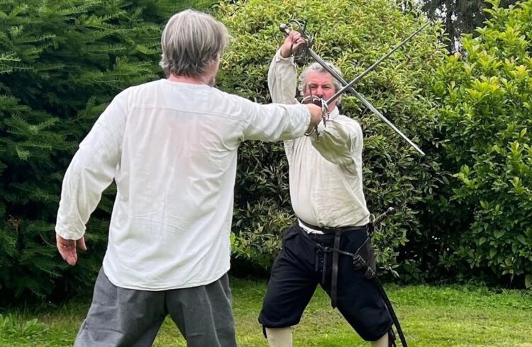 Two men practising fencing in period dress