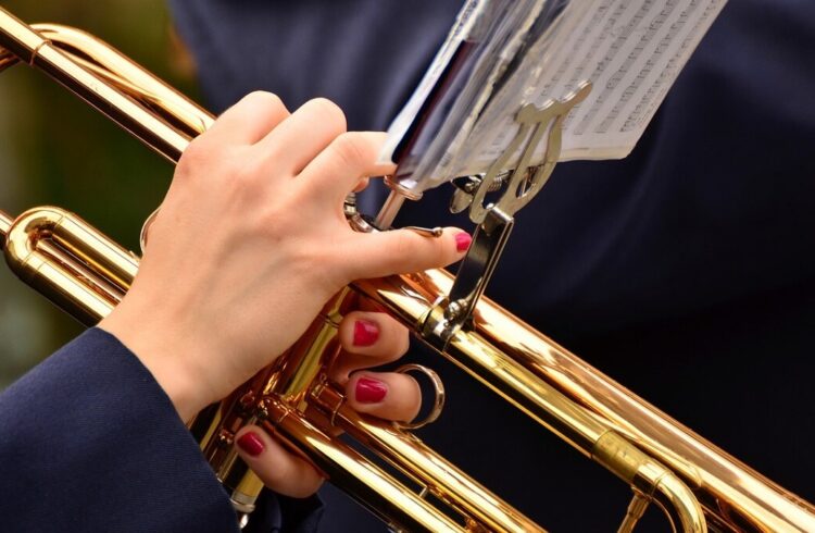 A musician with painted nails playing a trumpet