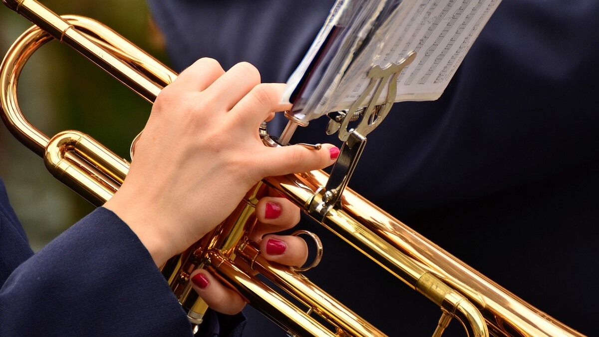 A musician with painted nails playing a trumpet