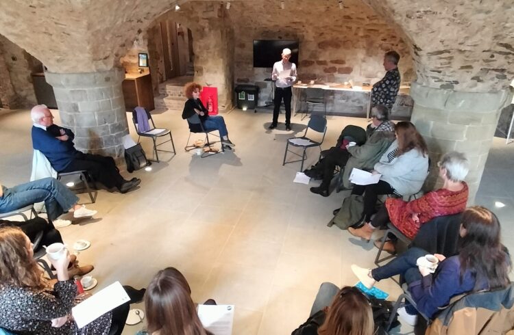 A group of people seated in a crypt, listening to a talk